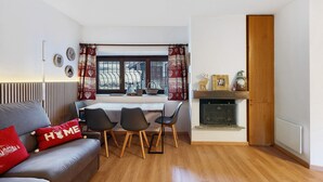Ein gemütliches Wohnzimmer mit einer Couch, einem Esstisch mit Stühlen, einem Kamin und einem Fenster mit Vorhängen.