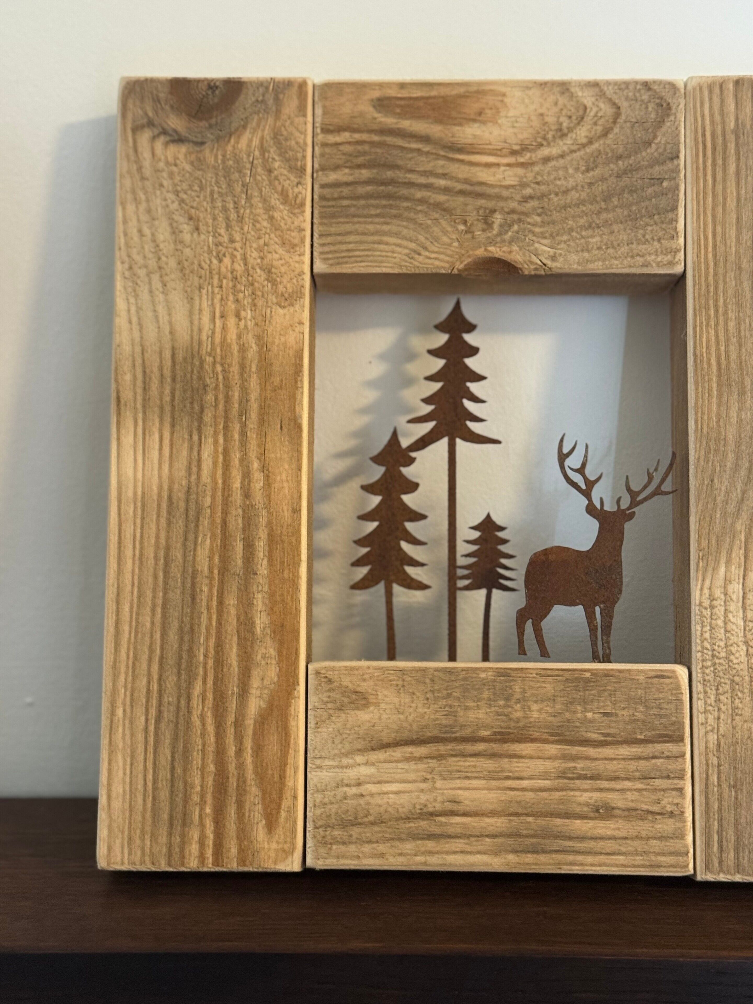 Un cadre en bois orné d’une découpe sur le thème de la nature, représentant des arbres et un cerf.