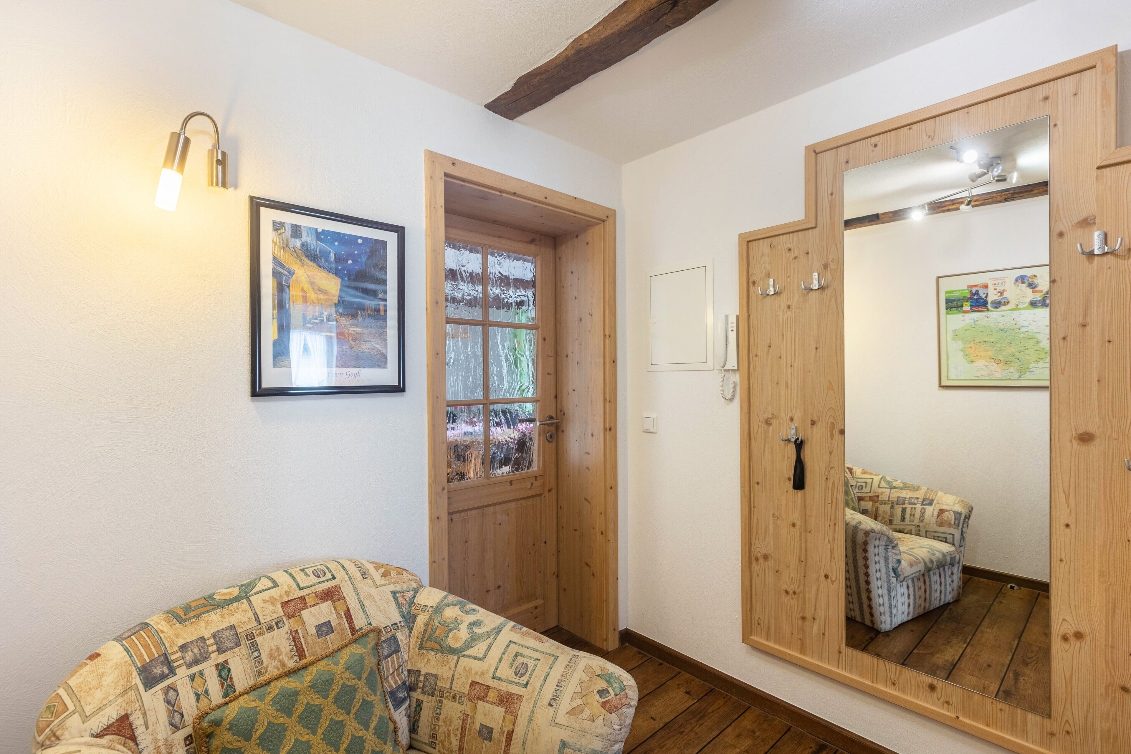Una habitación con un sofá estampado, una puerta de madera, un espejo y un cuadro enmarcado en la pared.