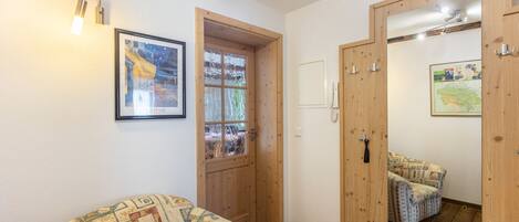 Una habitación con un sofá estampado, una puerta de madera, un espejo y un cuadro enmarcado en la pared.