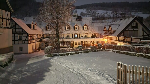 Een gebouw in traditionele Europese stijl met veel ramen en een besneeuwd landschap.