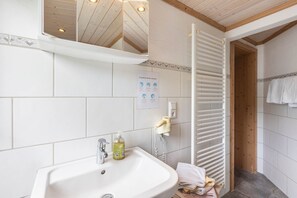 Een badkamer met een wastafel, spiegel, handdoekhouder en een houten deur.