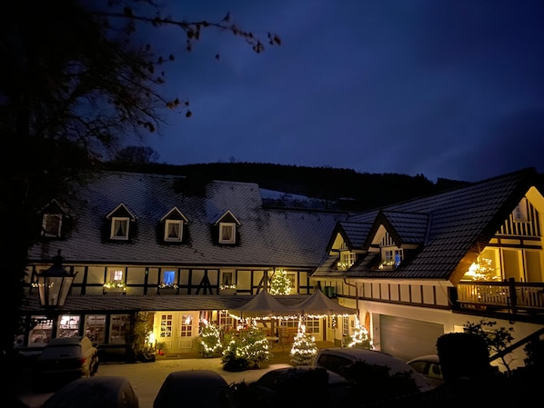A traditional building with multiple windows and a covered outdoor area with lights.
