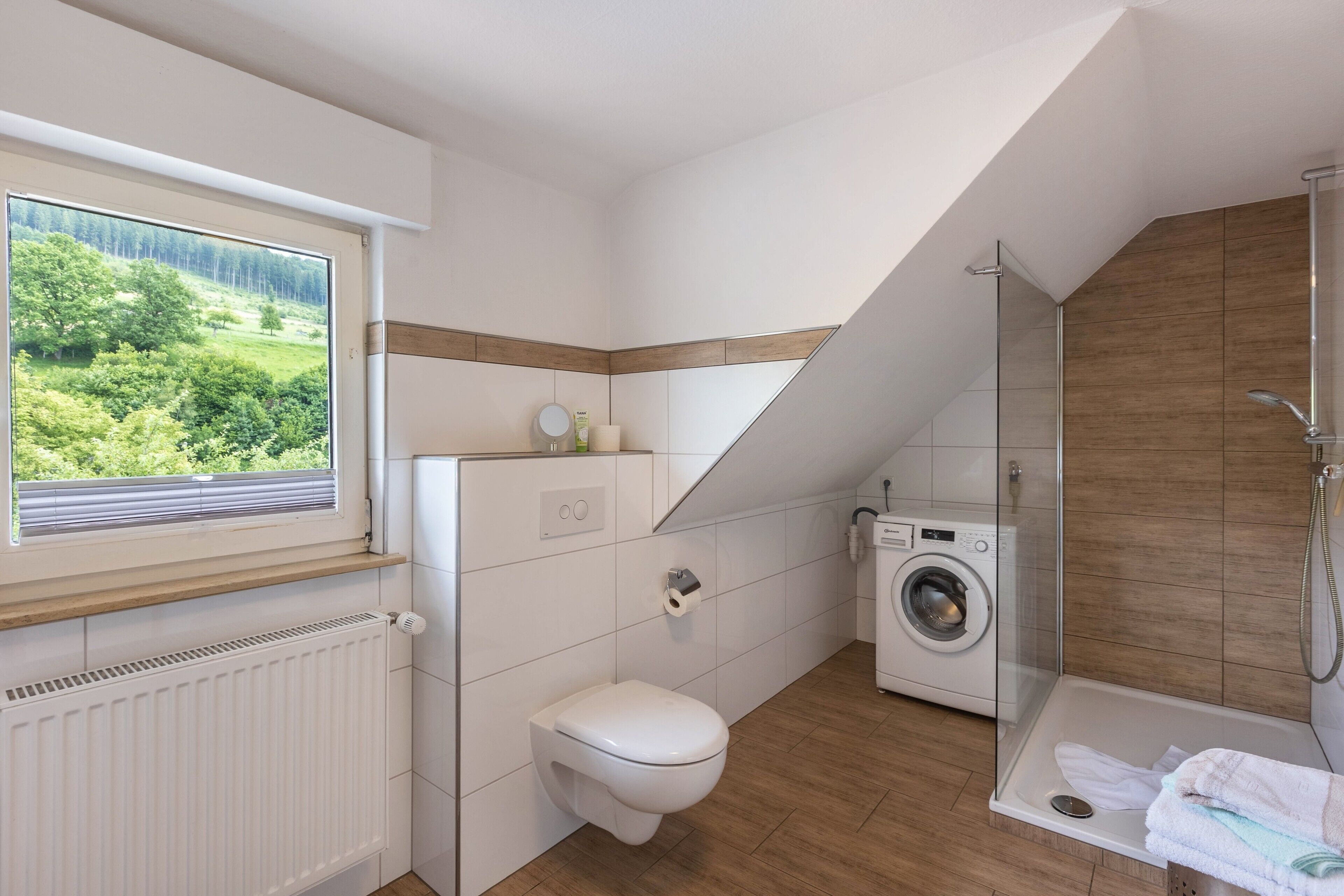 Ein modernes Badezimmer mit Toilette, Waschmaschine und Dusche.