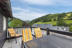 Ein Balkon mit Sitzgelegenheit und Blick auf eine grüne Landschaft.