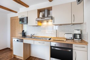 Eine kleine Küche mit Holzausstattung, einer Mikrowelle, einem Toaster, einer Kaffeemaschine und einem Geschirrspüler.