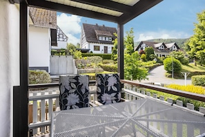 Ein Balkon mit Tisch und Stühlen mit Blick auf eine Wohngegend mit Häusern und Grünflächen.