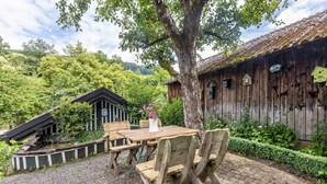 A rustic wooden table and chairs set on a cobblestone patio with a wooden fence and a tree in the background. - Apartment 'Romantik' with Shared Terrace, Balcony and Wi-Fi (Lennestadt)