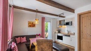 A cozy living room with a sofa, table, and chairs, a kitchen with modern appliances, and a wooden ceiling. - Apartment 'Romantik' with Shared Terrace, Balcony and Wi-Fi (Lennestadt)