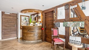 A reception area with a wooden reception desk, a red cushioned chair, and a wooden wall with various signs and decorations. - Apartment 'Romantik' with Shared Terrace, Balcony and Wi-Fi (Lennestadt)