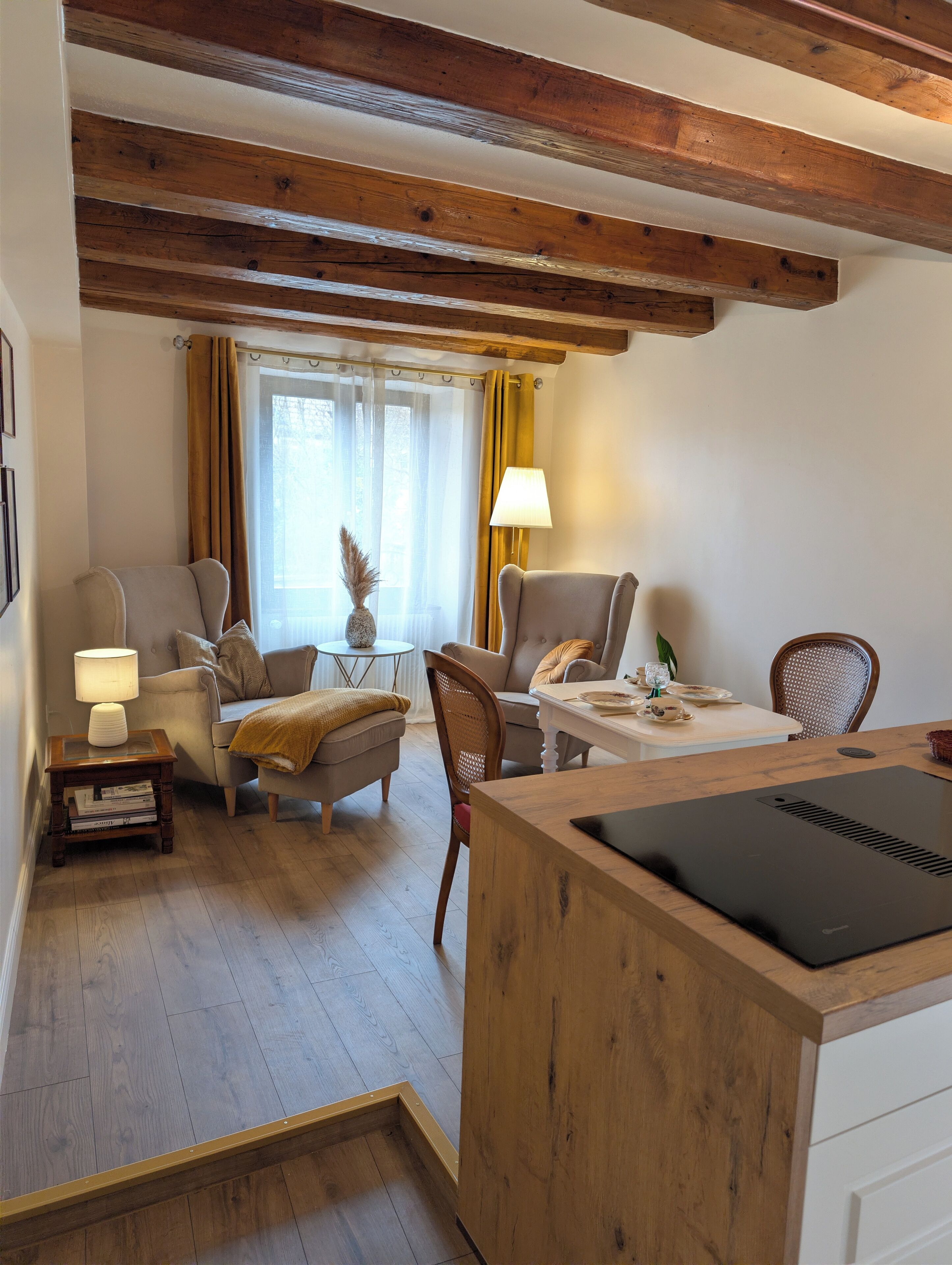 A cozy living room with a wooden ceiling, a sofa, a coffee table, and a dining table with chairs.