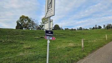 A parking sign with a bicycle symbol, a directional sign for 'Le Cerisier,' and a sign indicating a 2-hour parking limit.