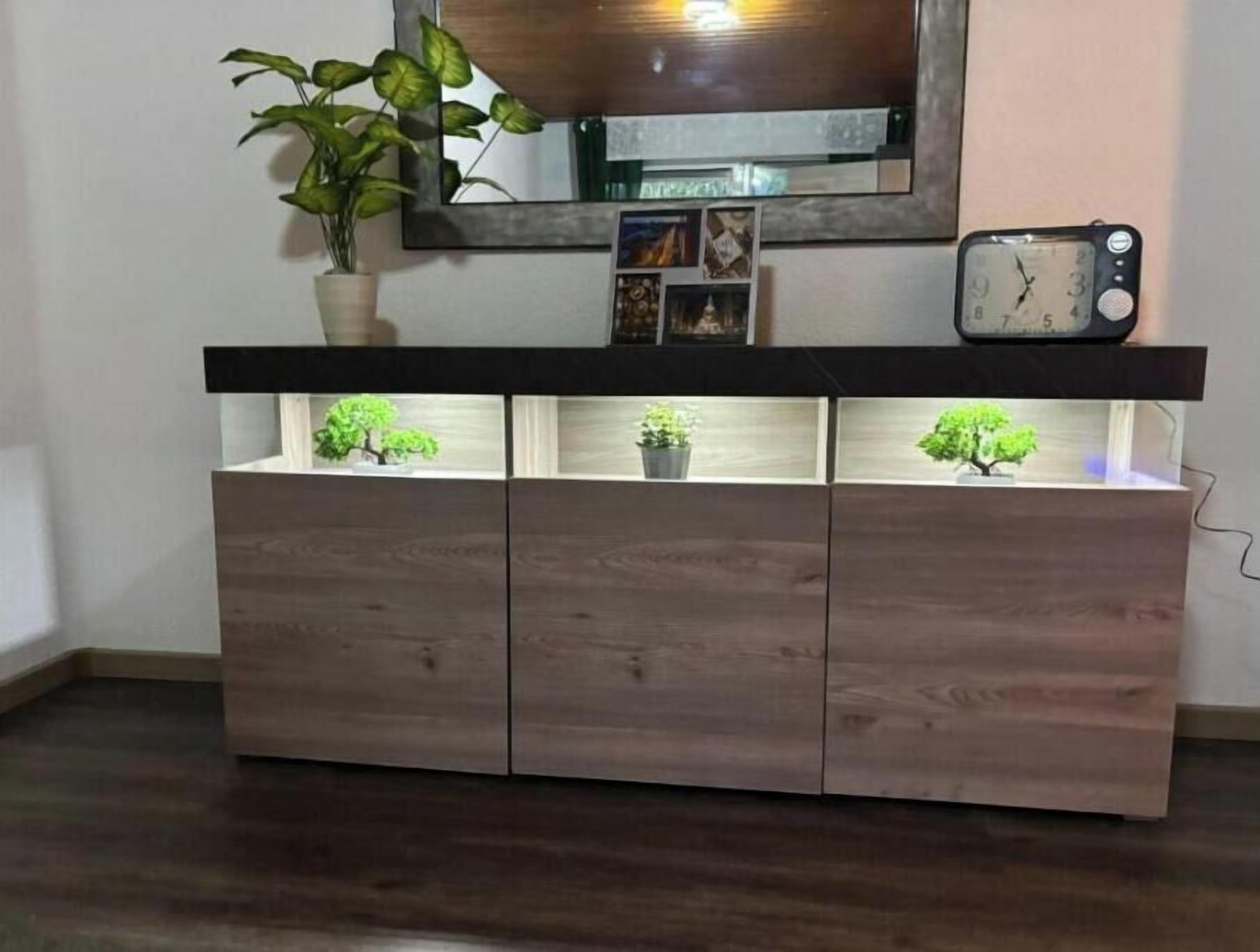 A wooden cabinet with three illuminated shelves, a clock, and a mirror above it.