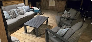 A cozy outdoor seating area with a grey sofa, two armchairs, and a small table.