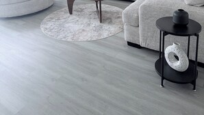 Ein modernes Wohnzimmer mit einem grauen Sofa, einem runden Couchtisch und einem kleinen Beistelltisch.