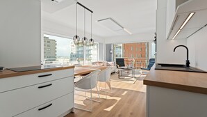 Een moderne keuken met witte kasten, een houten aanrecht en een eethoek met een tafel en stoelen.