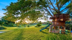 A playground with a slide and a wooden playhouse.