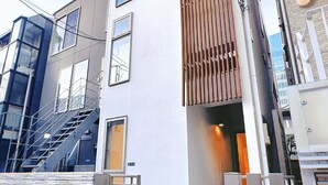 Un bâtiment moderne à la façade blanche, doté de nombreuses fenêtres et d’un portail en métal.