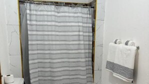 Ein Badezimmer mit Duschvorhang, Toilette, Handtuchhalter und Bodenfliesen mit Steinmuster.