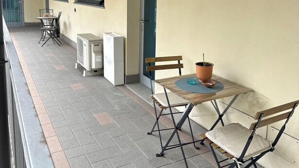 Un patio al aire libre con una mesa y sillas, una planta en maceta y una puerta que da a un edificio.