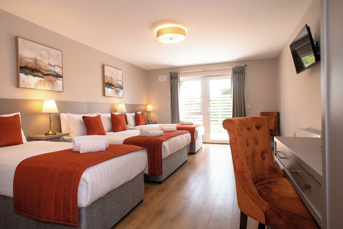 A hotel room with three beds, a desk, and a chair.