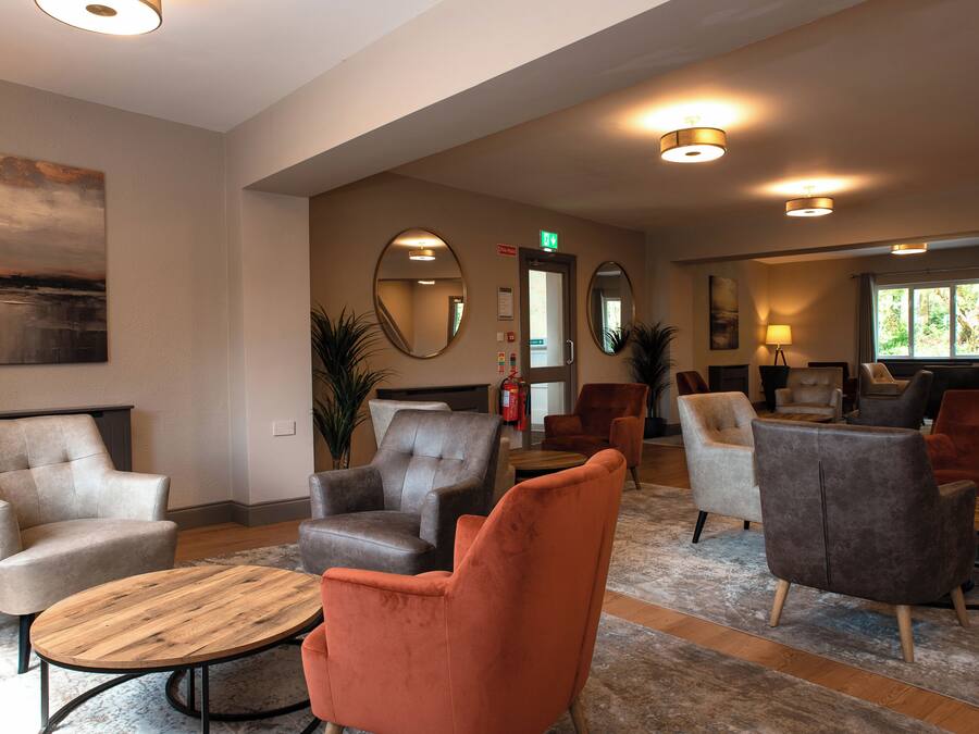 A lobby with multiple seating areas, a fire extinguisher, and a door with an exit sign.