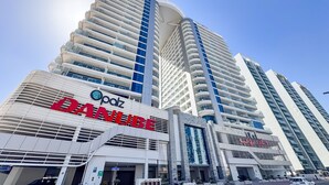 A modern hotel with a curved facade, multiple balconies, and a prominent 'Palz' sign. - PVH - Opalz by Danube 1BR with Jacuzzi (Dubai)