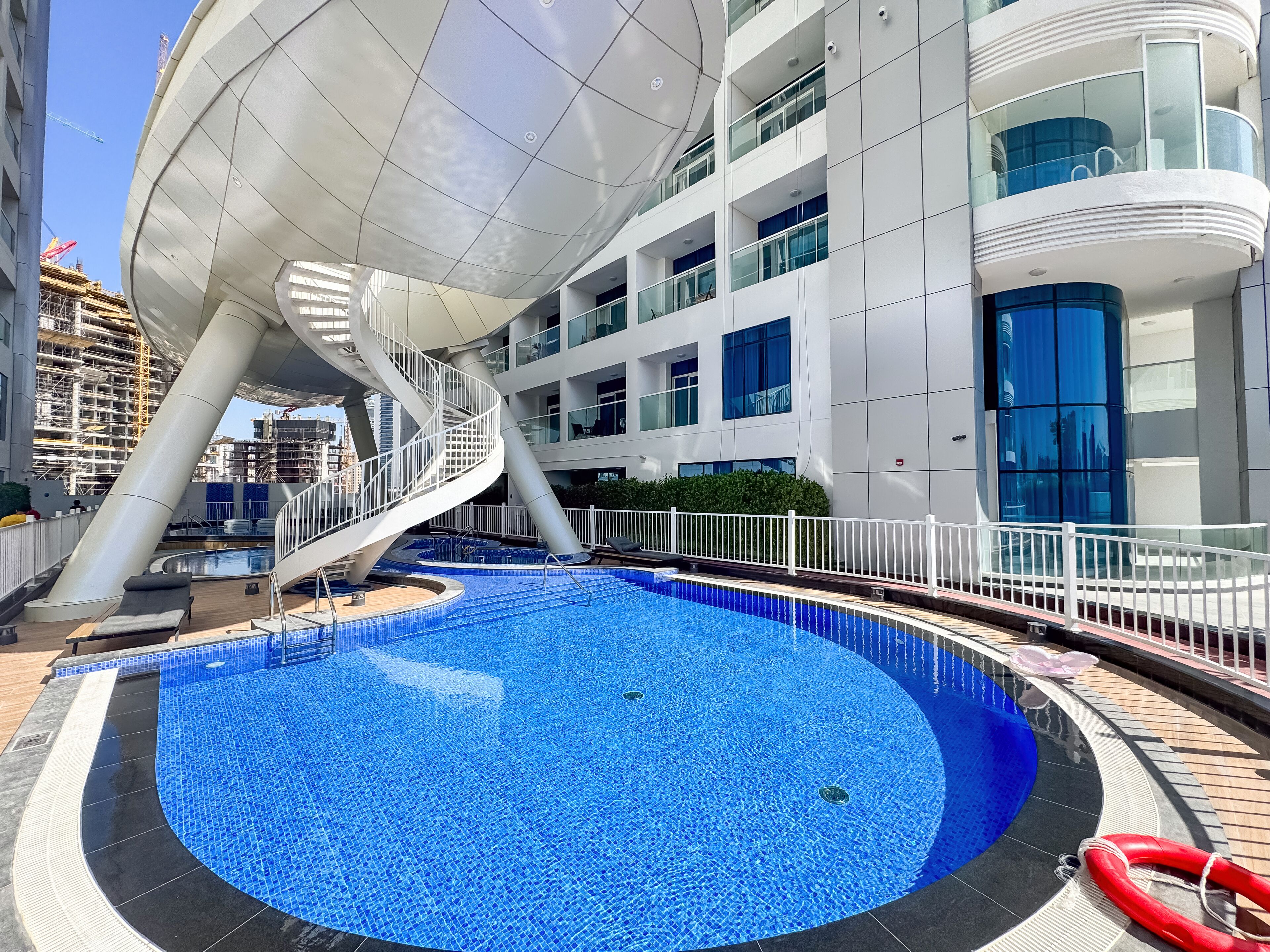 Un edificio moderno con zona de piscina, que incluye una piscina circular y un tobogán.