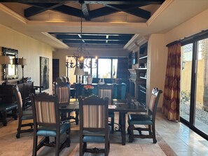 A spacious living room with a high ceiling, a chandelier, and a dining area with a glass table and chairs. - Elegant Novaispania 4BR house views Pacific next to Quivira Golf Cabo San Lucas (Cabo San Lucas)