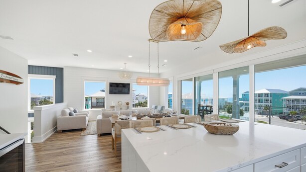 A spacious living area with a large island, modern furniture, and large windows offering a view of the surrounding area.