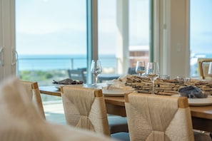 Una mesa de comedor con sillas, copas de vino y platos listos para una comida.