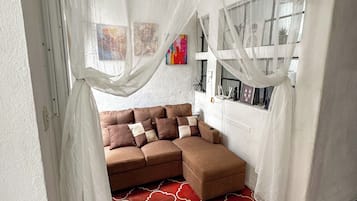 A cozy room with a sectional sofa, a patterned red carpet, and sheer curtains.