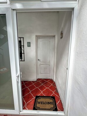 A white door with a 'WELCOME' mat in front.