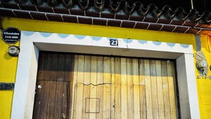 A large wooden door with a number 21 sign above it, set in a yellow building with a tiled roof. - Apto Maison | 5-minute walk from Central Park (Antigua Guatemala)