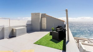 A rooftop terrace with a small seating area, a door, and a view of the sea. - Home2Book Cozy Sea View Apartment Near the Coast (Arico)