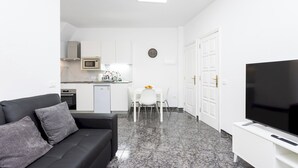 A modern living room with a black leather sofa, a flat-screen TV, and a dining area with a white table and chairs. - Home2Book Cozy Sea View Apartment Near the Coast (Arico)