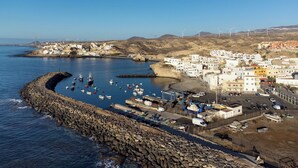 A coastal town with a rocky breakwater, boats, and wind turbines in the background. - Home2Book Cozy Sea View Apartment Near the Coast (Arico)