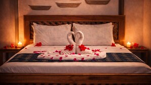 A neatly made bed with a towel artfully arranged in the shape of a bunny, surrounded by rose petals. - Nungwi Turtle Cave resort  (Nungwi)
