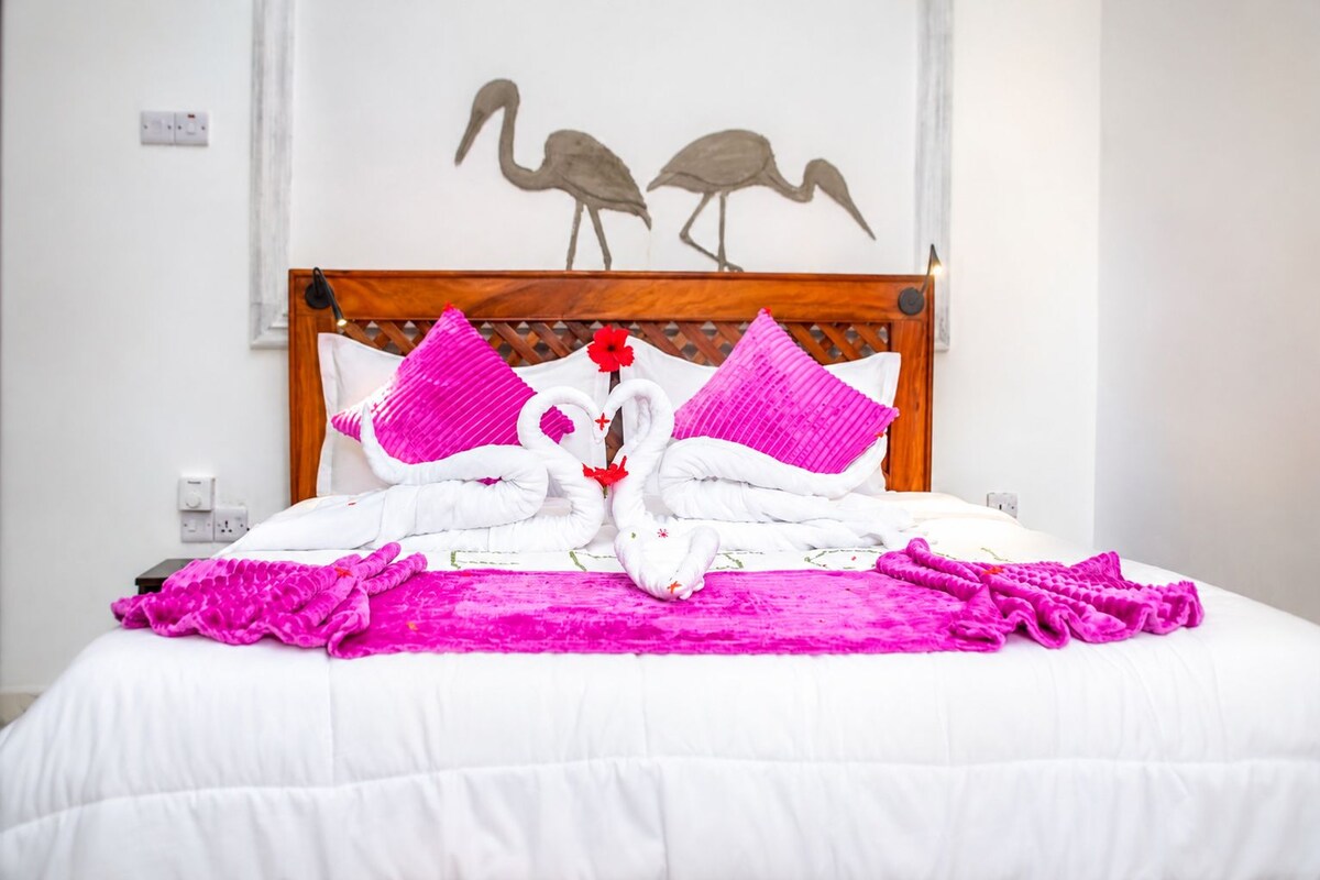 A neatly made bed with a white comforter and pink decorative pillows.