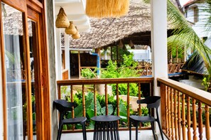 A balcony with wooden railings, black chairs, and hanging woven lamps.