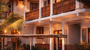A multi-story hotel with balconies, a covered outdoor area, and tropical plants. - Nungwi Turtle Cave resort  (Nungwi)