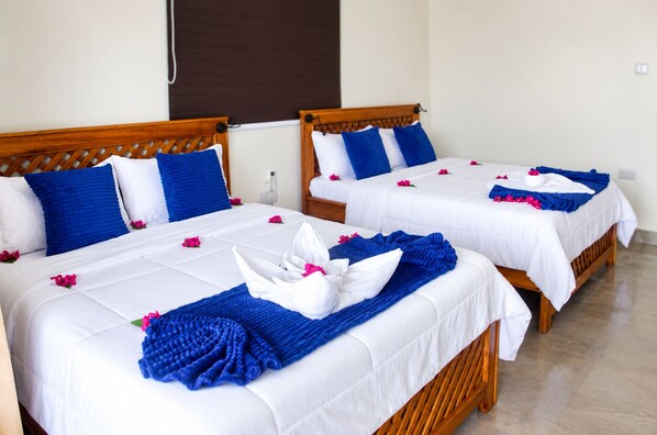 Dos camas dobles con ropa blanca, almohadas azules y toallas decorativas.