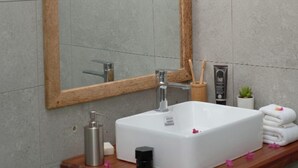 A bathroom with a wooden-framed mirror, a white sink, and a wooden vanity. - Nungwi Turtle Cave resort  (Nungwi)