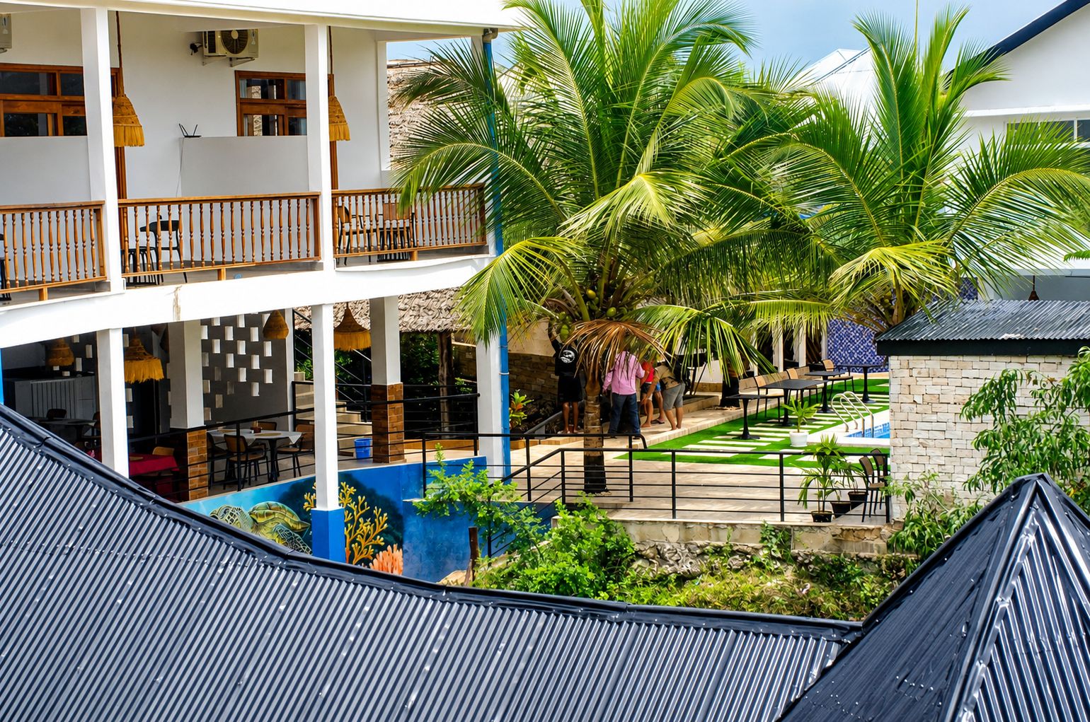 A multi-level building with outdoor seating areas, palm trees, and a staircase.
