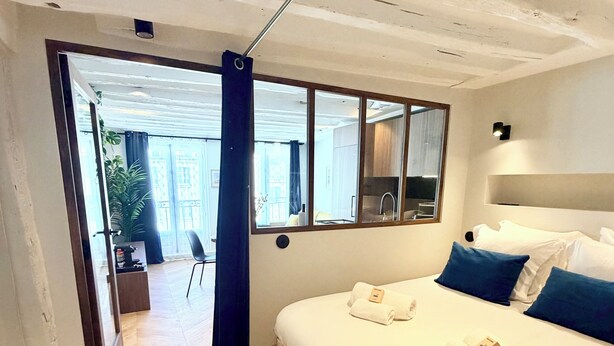 Ein modernes Hotelzimmer mit einem großen Bett, einem Spiegel und Blick ins Freie.