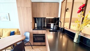 Eine moderne Küche mit Holzausstattung, einer schwarzen Arbeitsplatte und einem Essbereich mit Tisch und Stühlen.