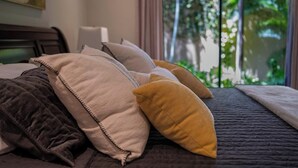 Ein Bett mit vielen Kissen und einer dunklen, gesteppten Bettdecke.