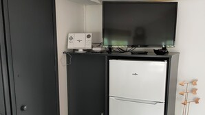A compact kitchenette with a white refrigerator, a black oven, and a small countertop with a coffee maker. - Superb location in the Var (Fréjus)