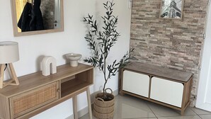 Un baño moderno con tocador de madera, espejo, inodoro de pared, planta decorativa e imagen enmarcada.