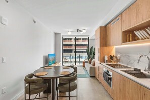 A modern kitchen with wooden cabinets, a built-in oven, and a large window overlooking a cityscape. - Modern Downtown 1BR | 15-Min Walk to FIFA Fan Fest (Miami)